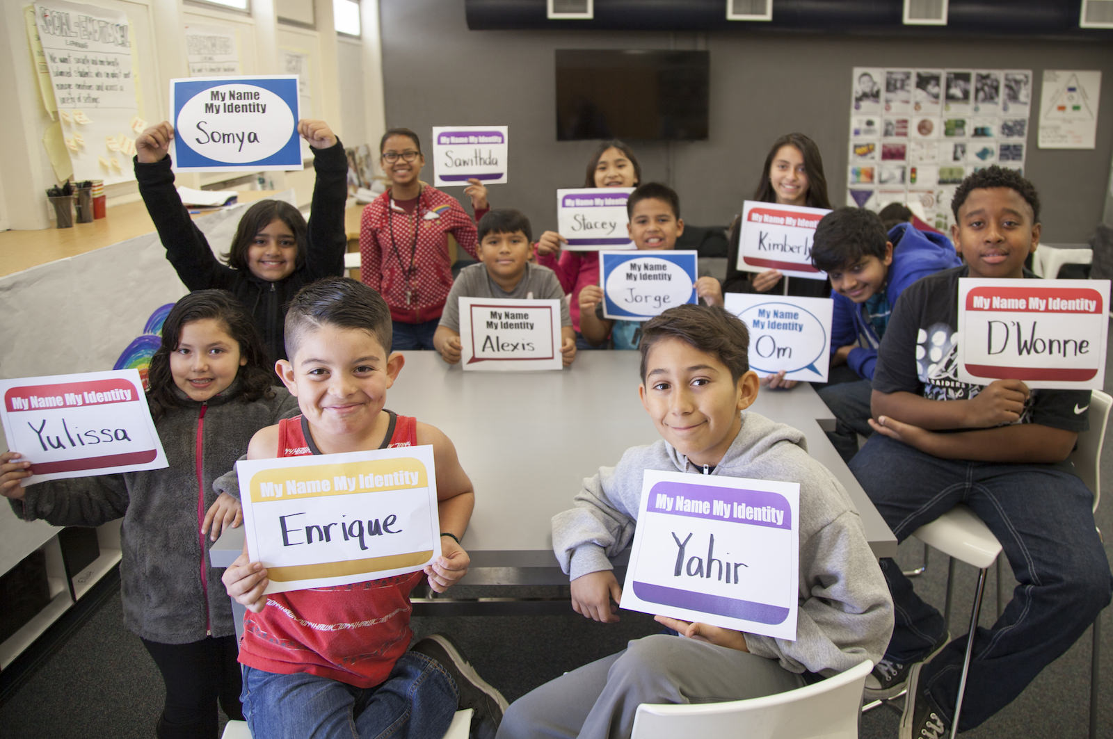 Students in a classroom holding up signs with their names on them